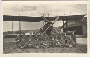 Fly og flyvere på Kjellerer UB småformat.  17 mann fremfor en dobbeltdekker med hangar bak.  Flott motiv