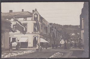 Drammen.  Uvanlig motiv fra Schwenckegaden  med W.C.Möller sin bygård med flagg og feststemte folk  stemplet 1910