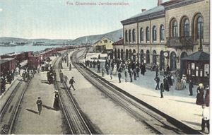 Jernbane Drammen Jernbanestation  (NK863) flott kolorert kort med tog og mennesker